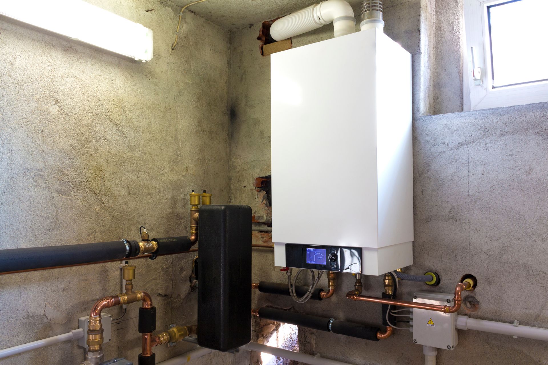 Chaudière murale gaz et son circuit dans une chaufferie, installée par Atout Travaux