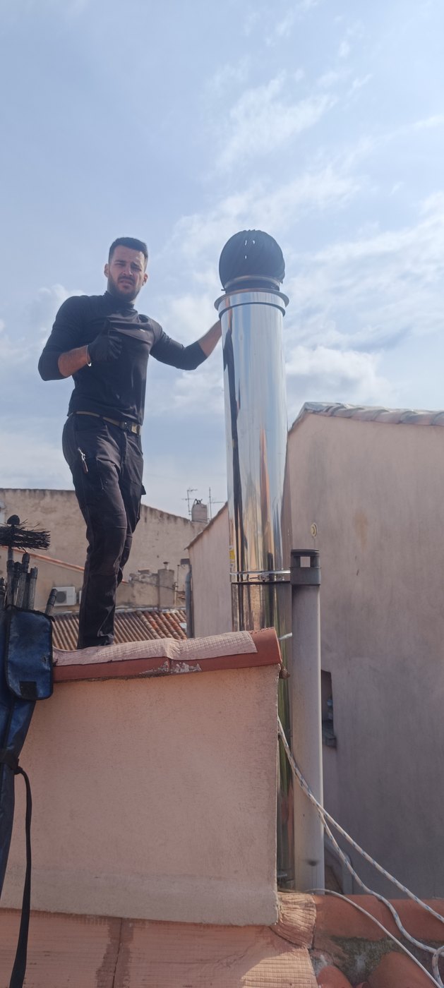 Ramoneur d'Atout Travaux sur un toit, à côté d'un conduit inox